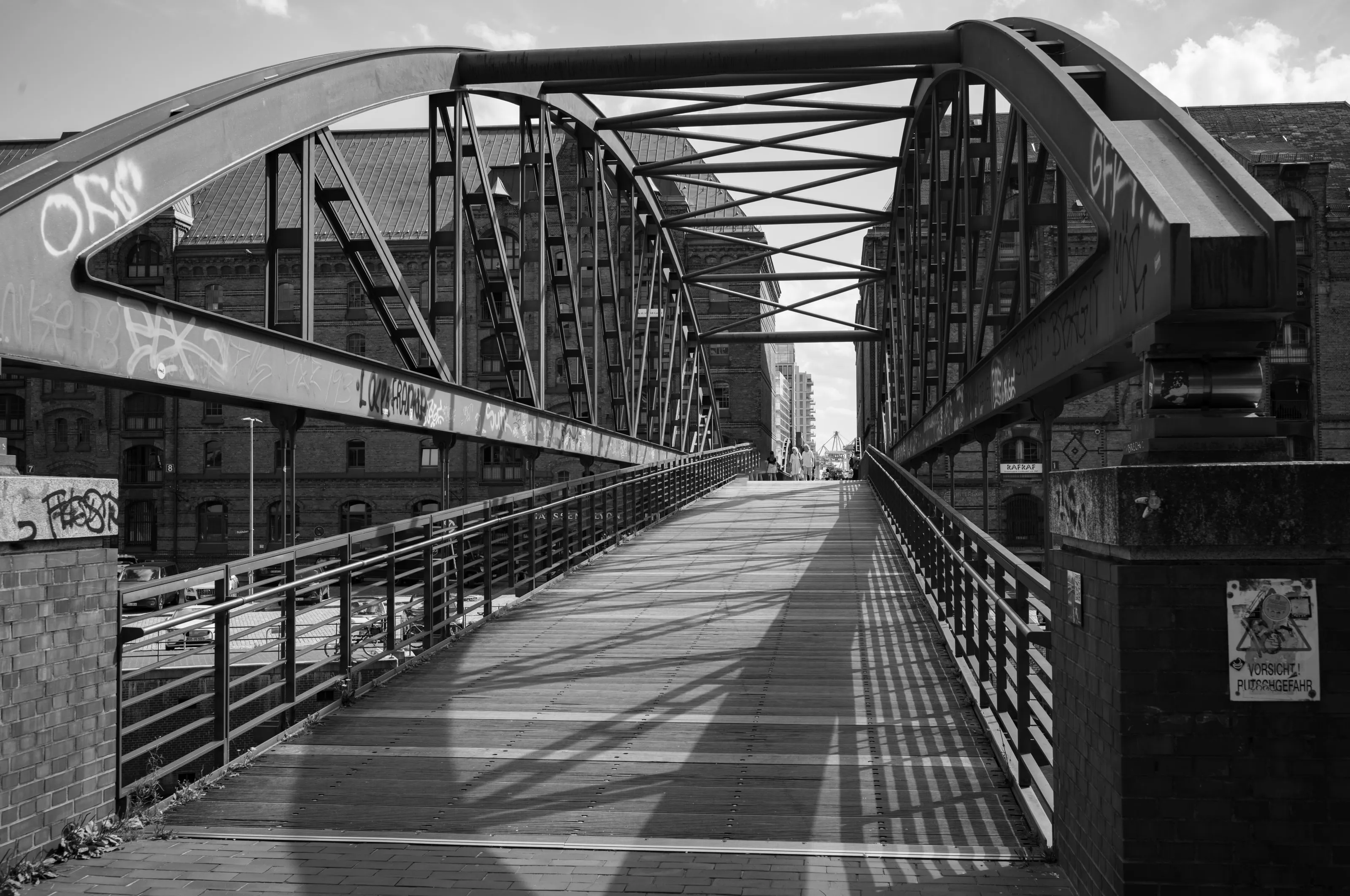 Fußgängerbrücke mit eisernen Bögen und langen Schatten