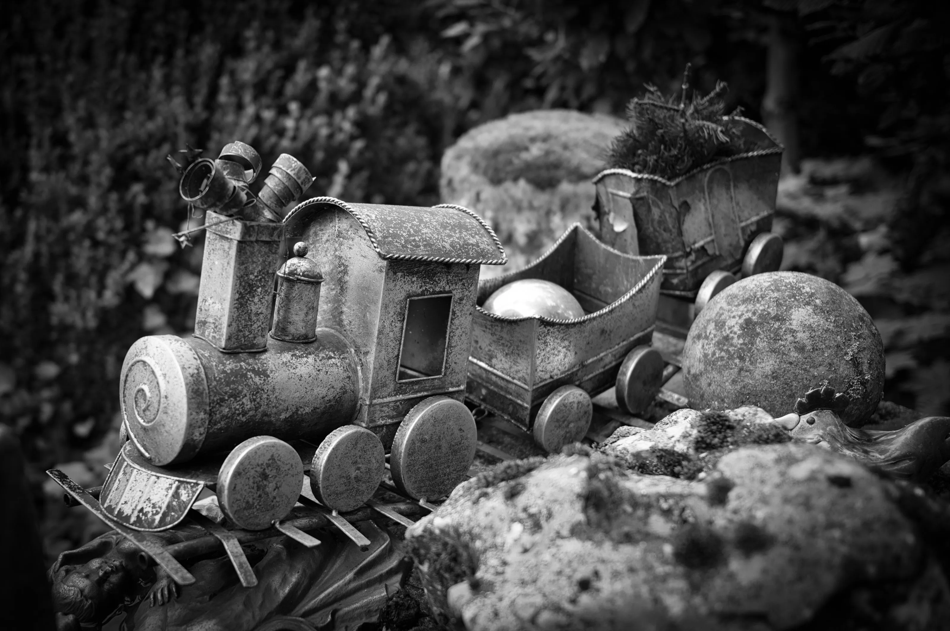 Alte Blecheisenbahn zwischen Moos und Steinen im Garten